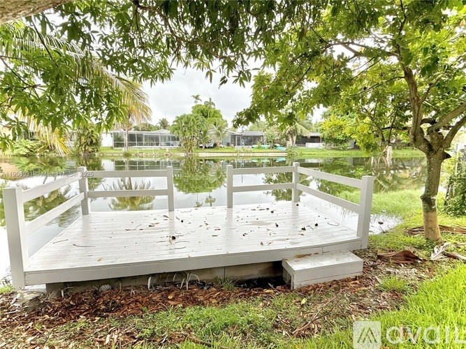A white wooden bridge over a pond surrounded by trees.