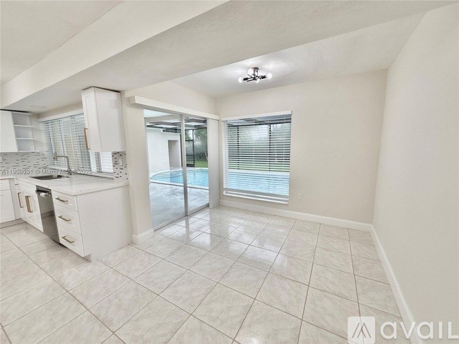 A spacious kitchen with white appliances and a large window.
