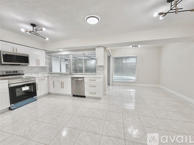 A spacious kitchen with white cabinets and a black oven.