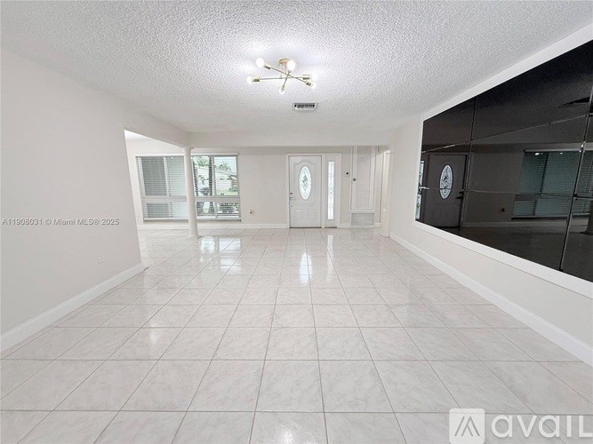 A spacious room with white tiled flooring and a ceiling fan.