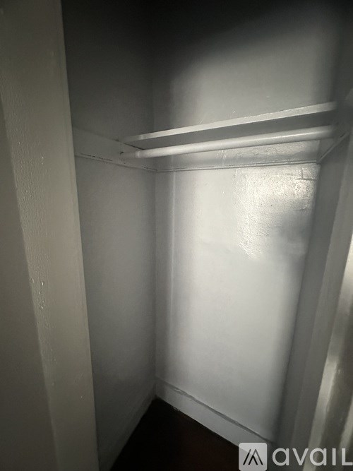 A small, dark room with a white door on the left and a white wall on the right.