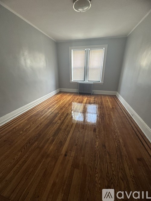A room with wooden flooring and a window with blinds.