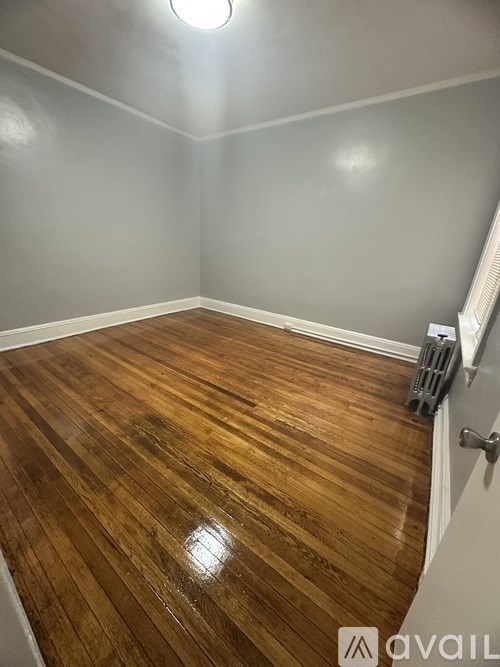 A room with wooden flooring and a white wall.