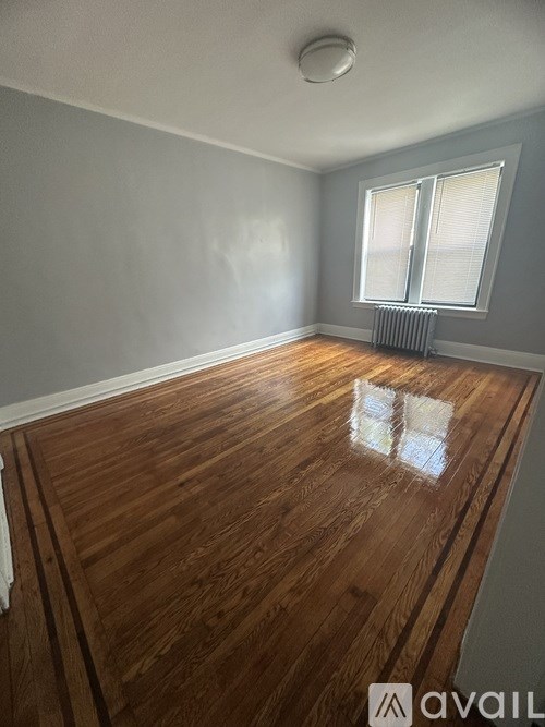 A room with wooden flooring and a window with blinds.