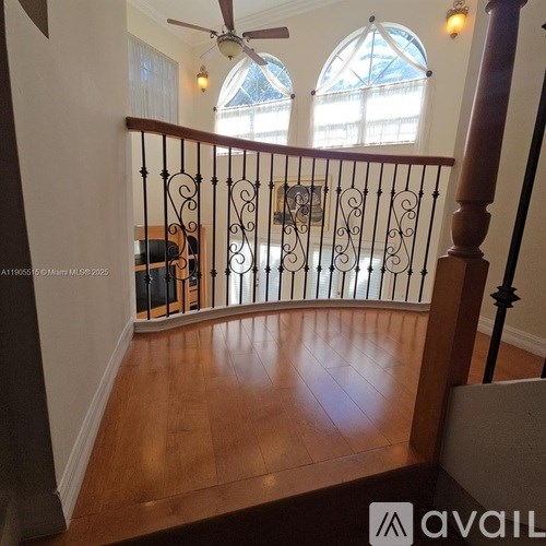 A wooden staircase with a metal railing and a ceiling fan.