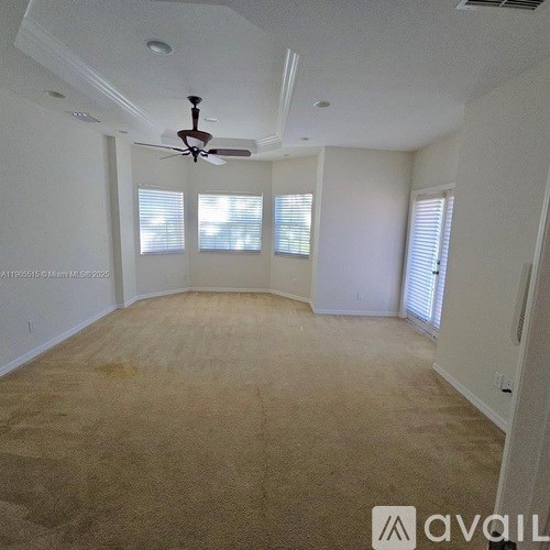 A room with a ceiling fan and carpeted floor.