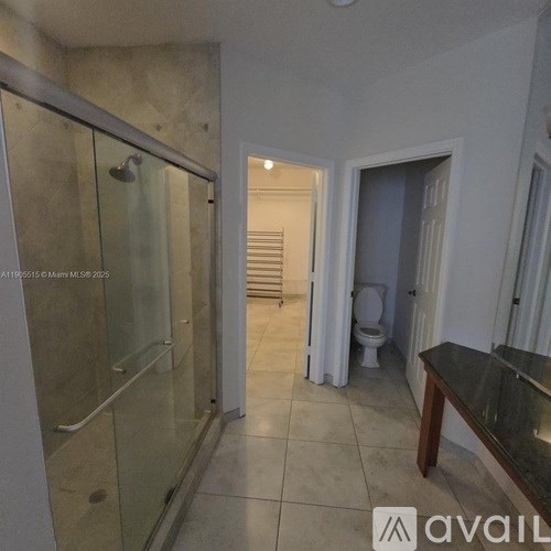 A bathroom with a glass shower stall and a toilet in the background.