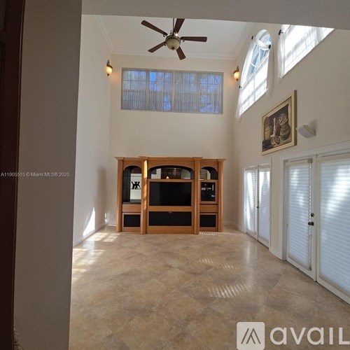 A living room with a wooden entertainment center and a ceiling fan.