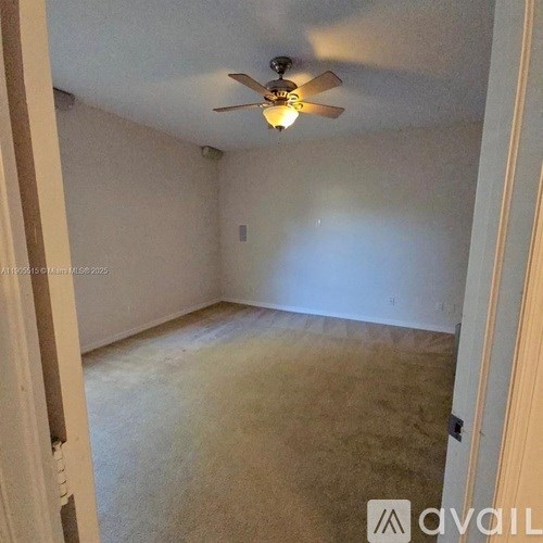 A room with a ceiling fan and carpeted floor.
