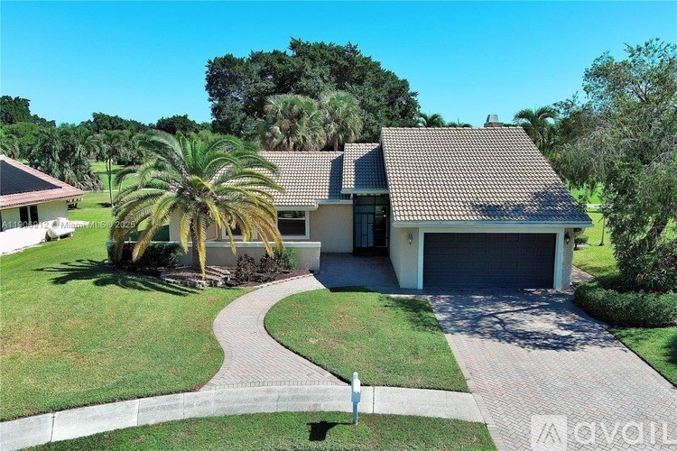 A house with a driveway and a palm tree in front.