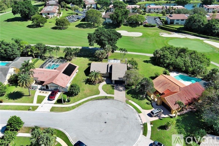 A bird's eye view of a residential area with houses, trees, and a swimming pool.