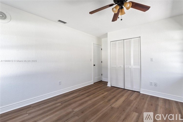 A room with a ceiling fan and wooden flooring.