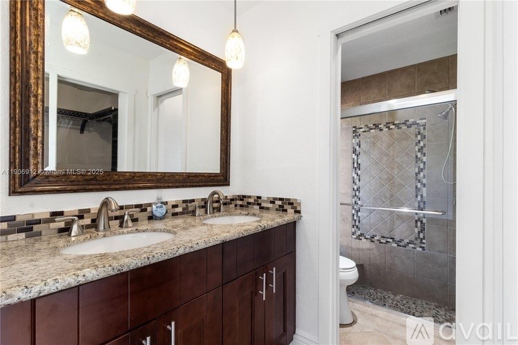 A bathroom with a granite countertop and a large mirror.