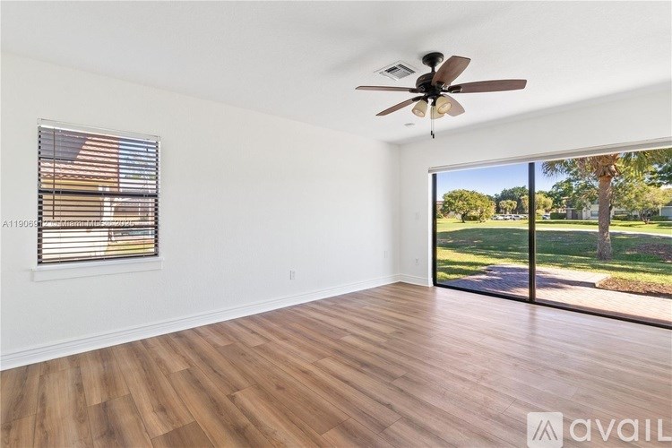 A room with a ceiling fan and sliding glass doors.