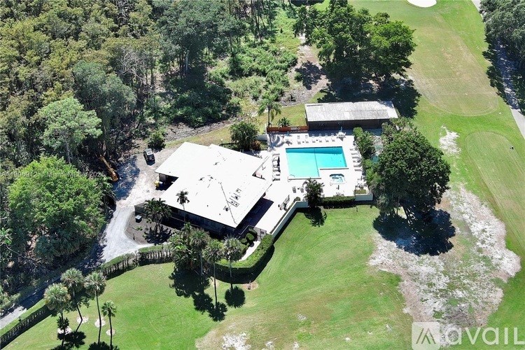 A large house with a pool surrounded by a green lawn.