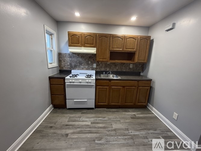 A kitchen with a white stove top oven and wooden cabinets.
