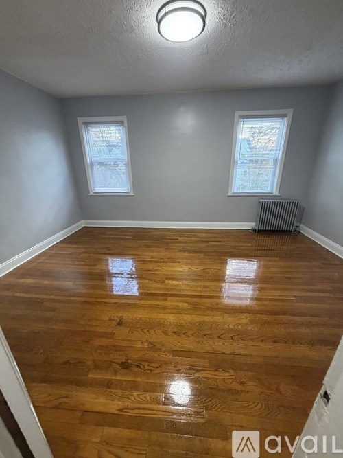 A room with wooden flooring and two windows.