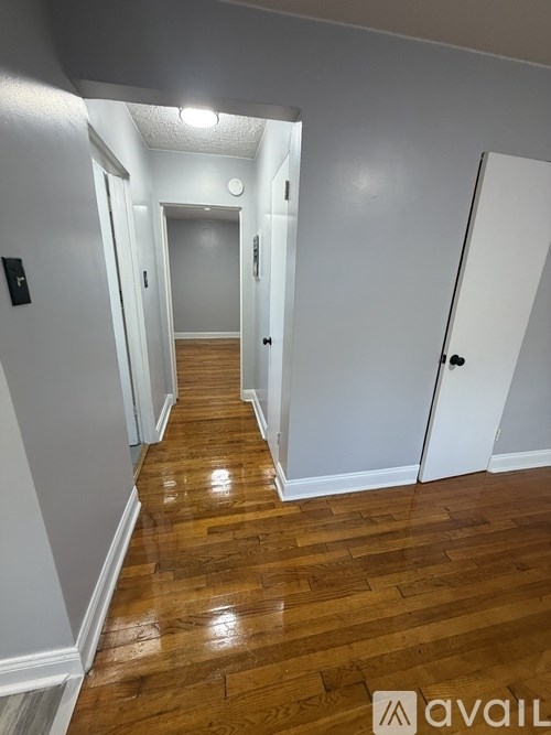 A hallway with wooden floors and white walls.