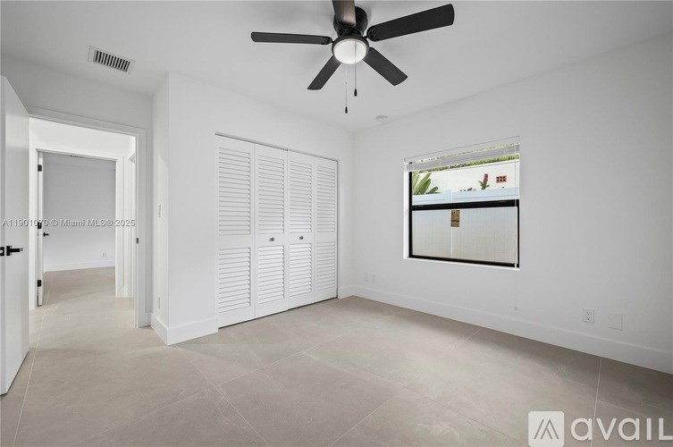 A spacious room with a ceiling fan and a window with blinds.