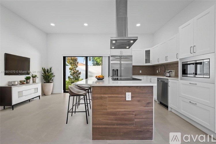 A modern kitchen with white cabinets and a wooden island.