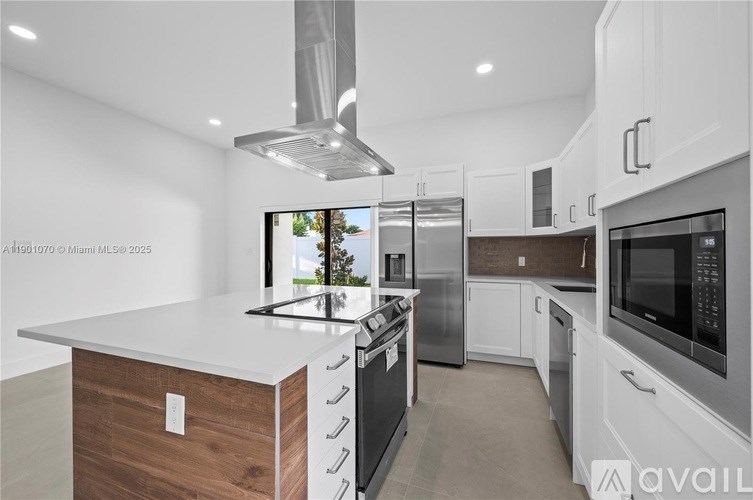 A modern kitchen with stainless steel appliances and a wooden island.