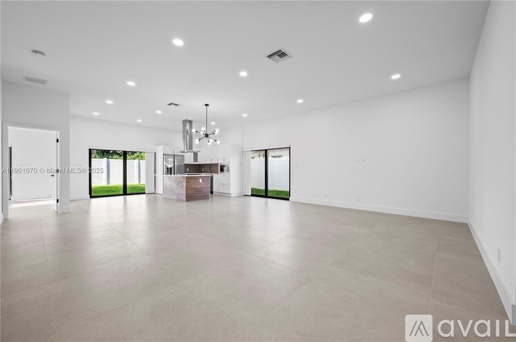 A spacious room with a chandelier and a cabinet in the middle.