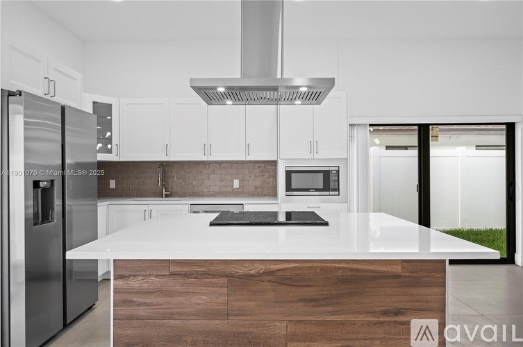 A modern kitchen with a white countertop and stainless steel appliances.