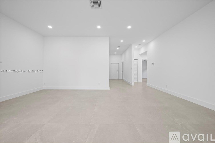 A spacious, empty room with white walls and a tiled floor.