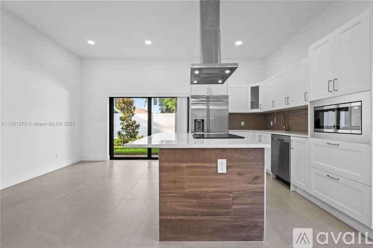 A modern kitchen with white cabinets and a wooden island.