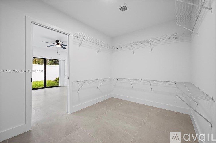 A spacious room with a ceiling fan and a door leading to a balcony.