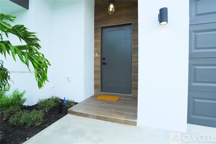 A modern house entrance with a grey door and a wooden step.