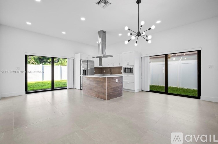 A modern kitchen with a large island and a chandelier hanging from the ceiling.