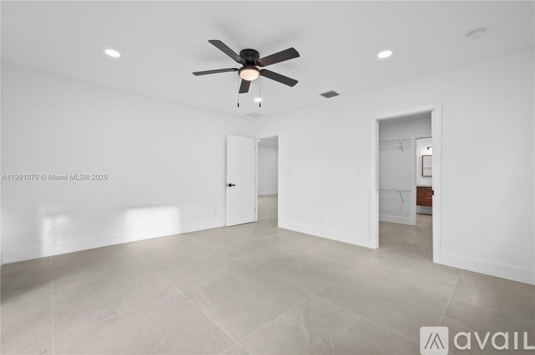 A spacious room with a ceiling fan and tiled flooring.