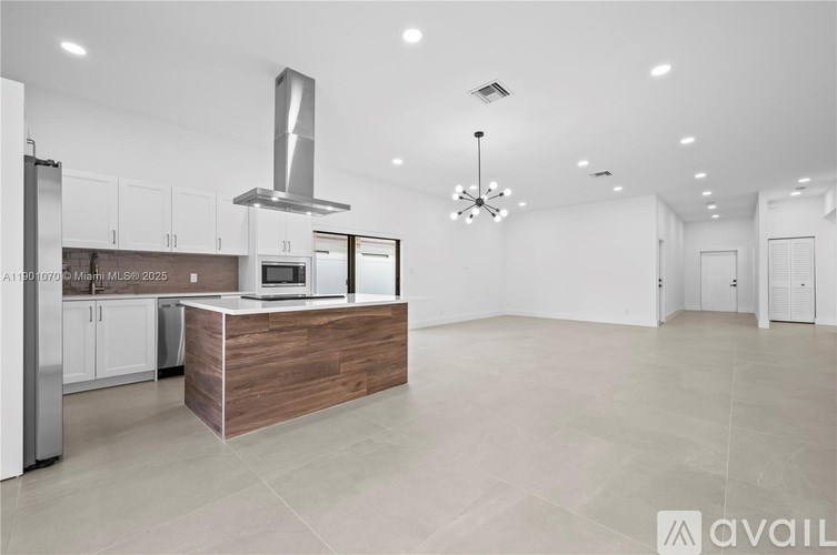 A modern kitchen with a wooden island and stainless steel appliances.