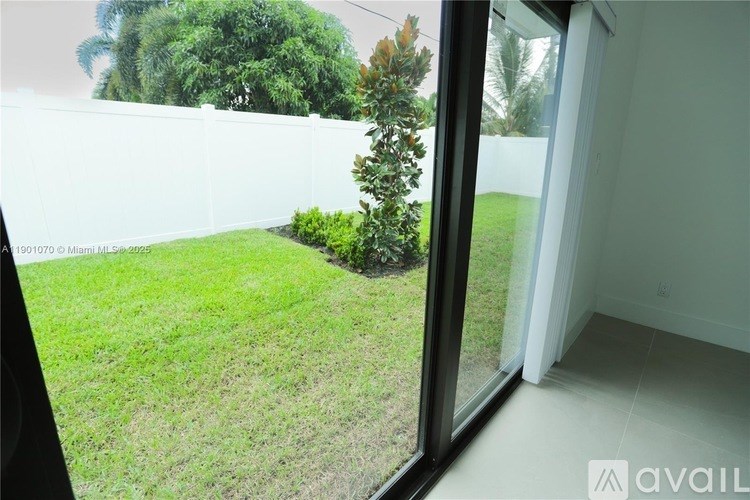 A small tree is in a yard seen through a glass door.
