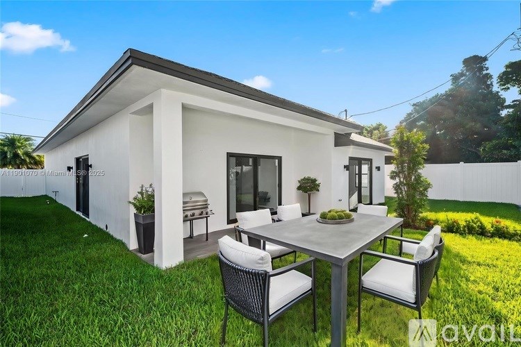 A white house with a patio table and chairs in front.