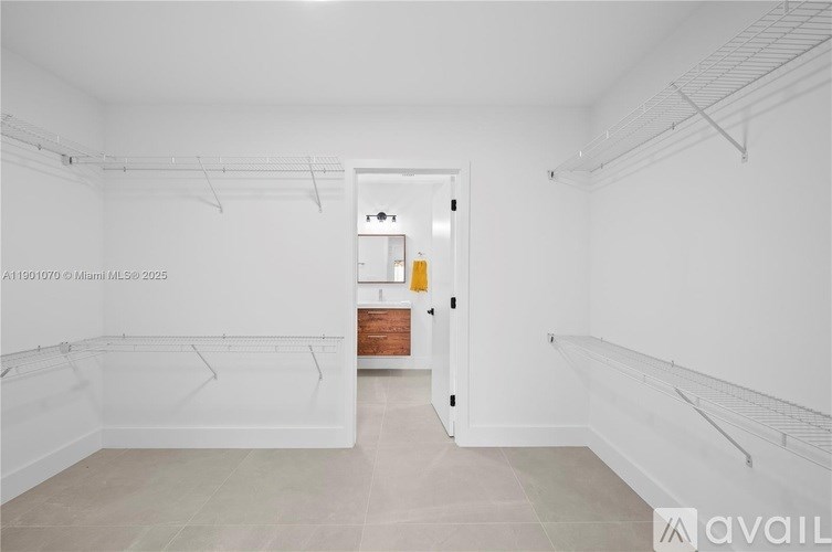 A spacious room with white walls and a doorway leading to another room.