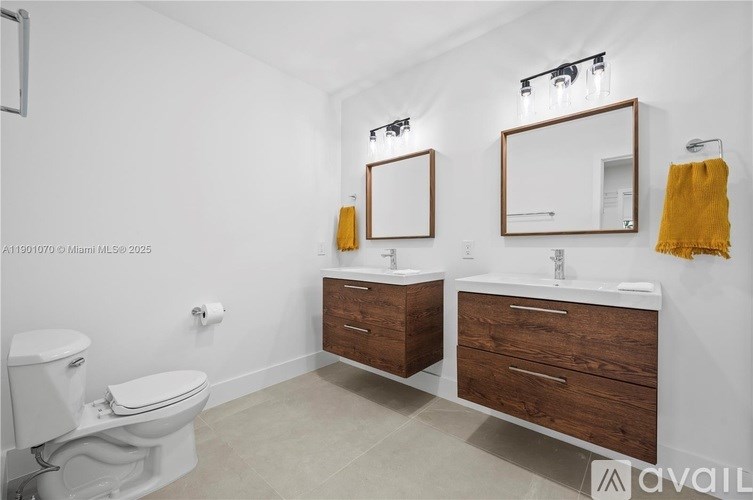 A bathroom with a toilet, sink, and mirrors.