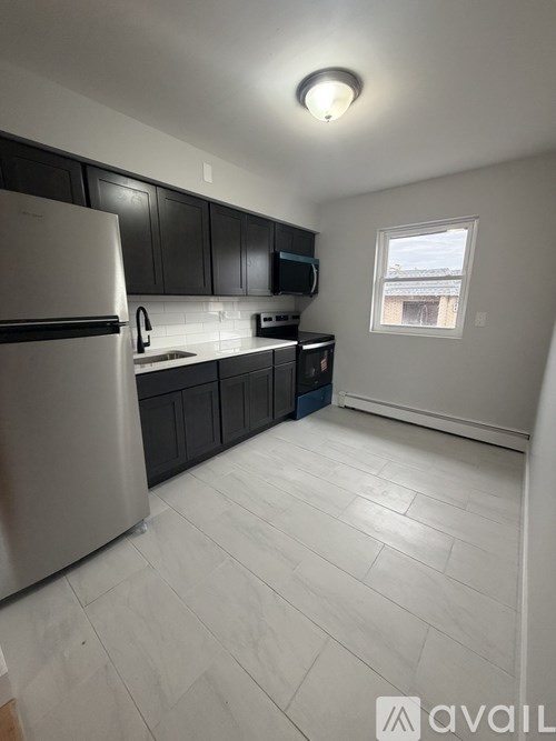 A kitchen with a white refrigerator and black cabinets.