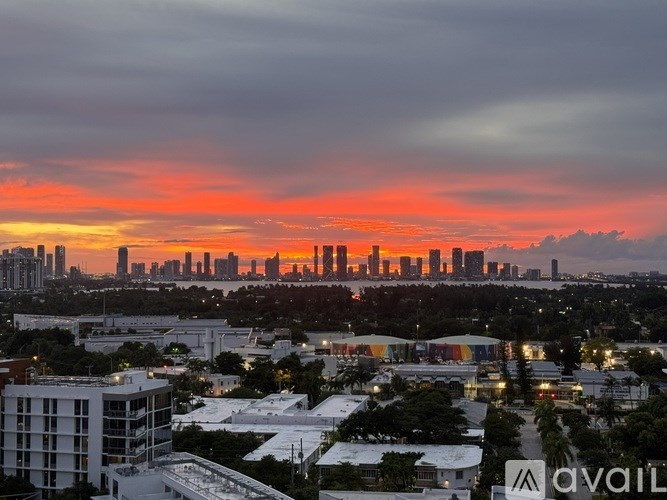 A city skyline at sunset with buildings illuminated against a darkening sky.