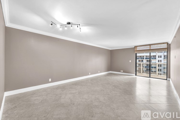 A spacious empty room with a sliding glass door leading to a balcony.