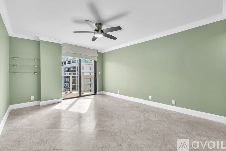 A room with a ceiling fan and a sliding glass door leading to a balcony.