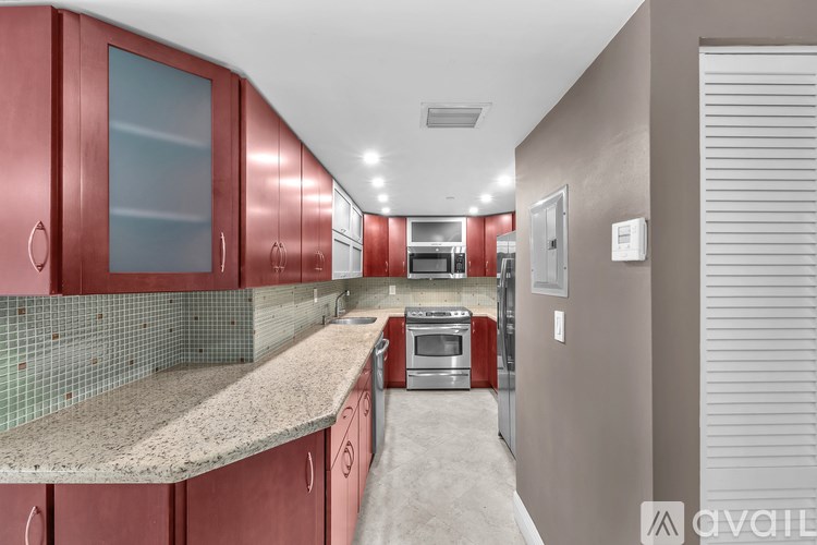 A kitchen with red cabinets and a granite countertop.