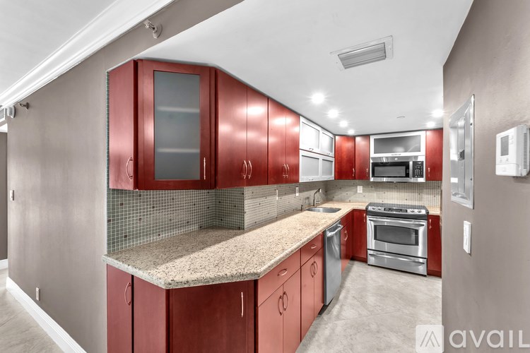 A kitchen with red cabinets and a granite countertop.