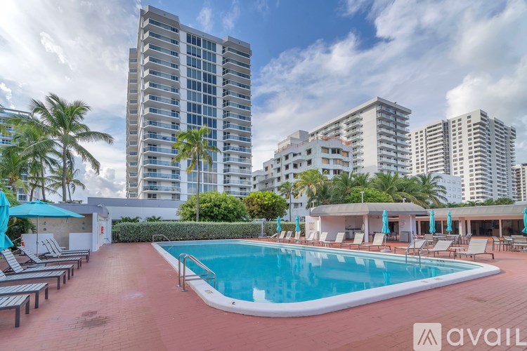 A pool area with lounge chairs and umbrellas in front of apartment buildings.