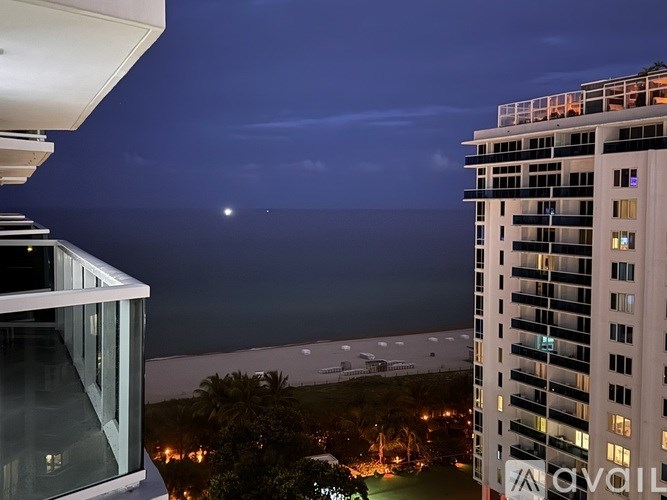 A modern building with a balcony overlooks a cityscape at night.