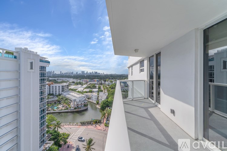 A modern white building with a balcony overlooking a cityscape and a river.
