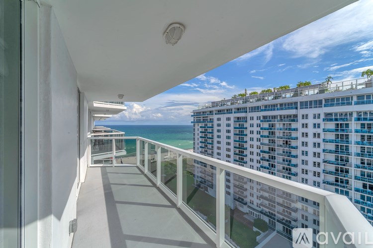 A balcony with a view of the ocean and a building in the background.