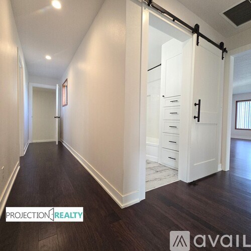 A hallway with white doors and dark wood floors.