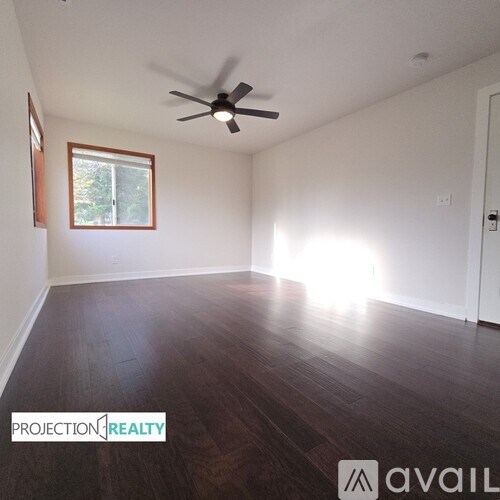 A room with a ceiling fan and wooden flooring.